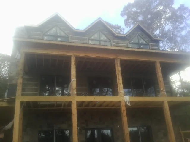 Dormers and porch framing on a large log home under construction — Roof Coating work by our crew in Peoria