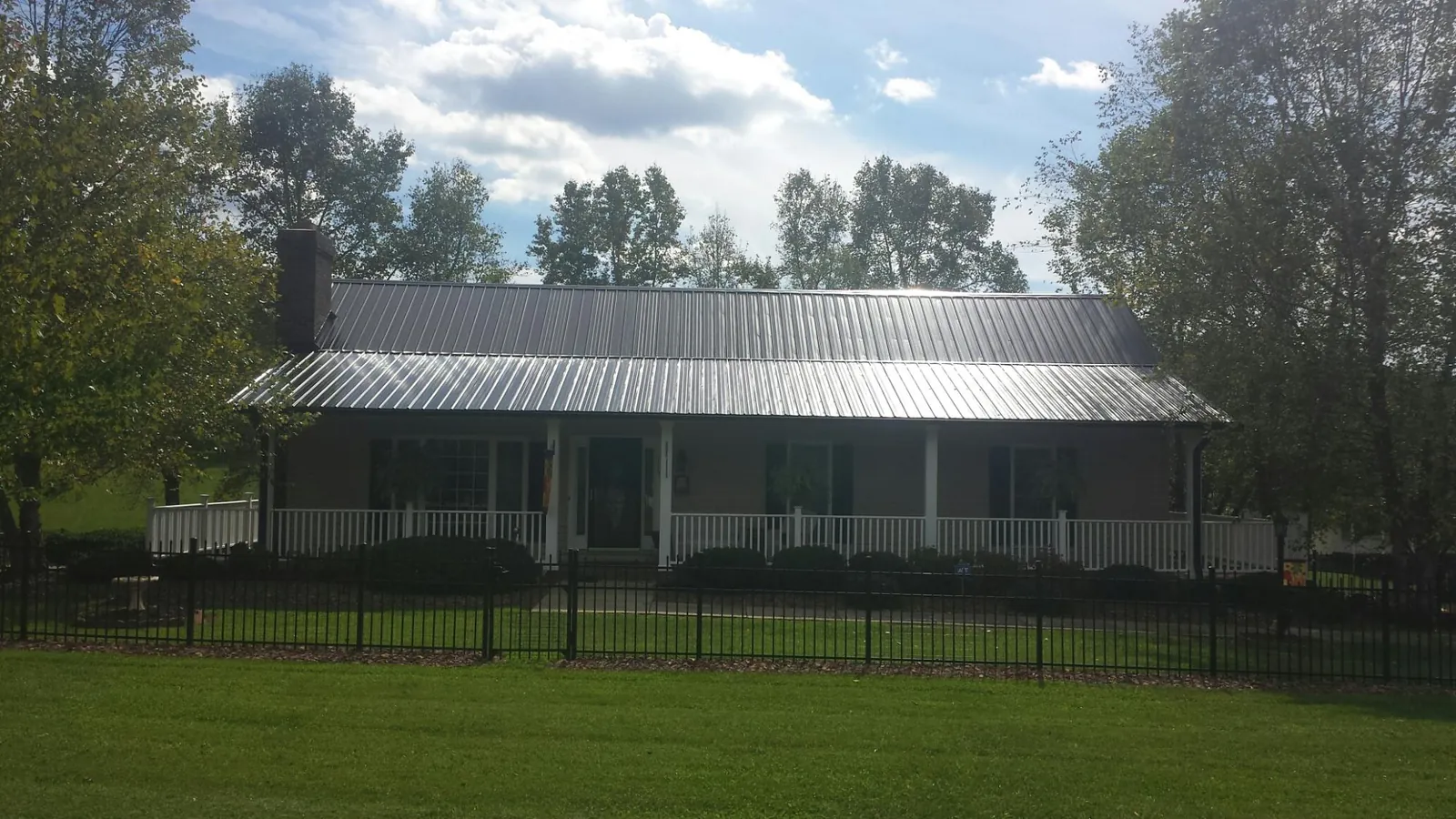 Gray metal roof on a brick ranch with a full width front porch — Gutter Guard Installation work by our crew in Peoria